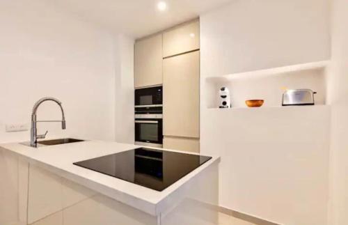 une cuisine blanche avec un évier et une cuisinière dans l'établissement Appartement 2 pieces Boulogne-Billancourt, à Boulogne-Billancourt