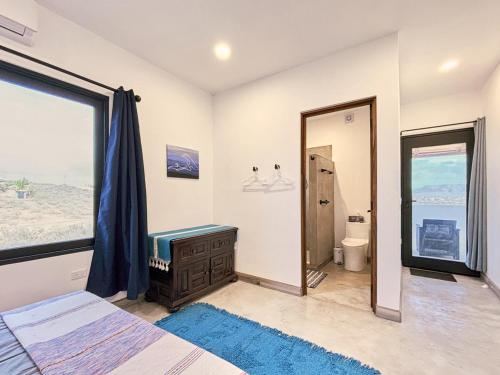 a bedroom with a bed and a bathroom with a window at 2 Casas and Pool- Walk to Beach, Great for Groups in El Pescadero