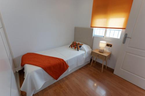 a small white bedroom with a bed and a table at Comeback UNFORGETTABLE in Salobreña