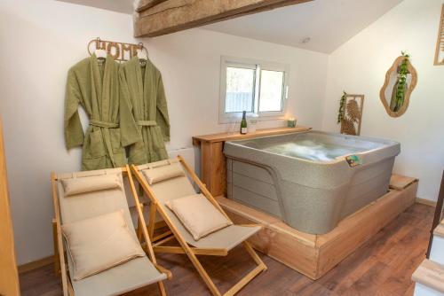 a bathroom with a tub and chairs in it at Les Suites C&S in Aufferville