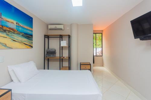 a bedroom with a white bed and a tv at Hotel Tropical San Jeronimo in San Jerónimo