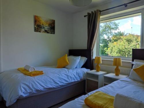 a bedroom with two beds and a window at 4-bed quiet cul de sac location with large secure off road parking for 4 cars in Timperley