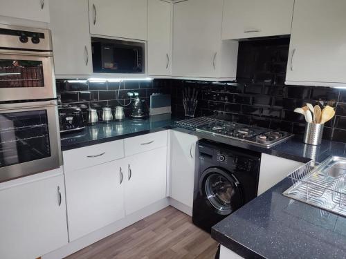 a kitchen with white cabinets and a washing machine at 4-bed quiet cul de sac location with large secure off road parking for 4 cars in Timperley