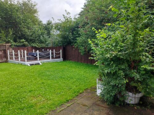 a garden with a fence and a bench in the grass at 4-bed quiet cul de sac location with large secure off road parking for 4 cars in Timperley