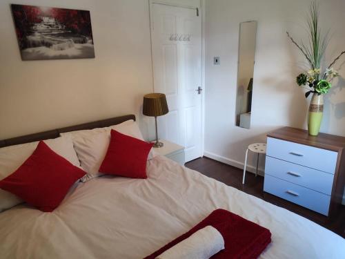 a bedroom with a bed with red pillows and a dresser at 4-bed quiet cul de sac location with large secure off road parking for 4 cars in Timperley