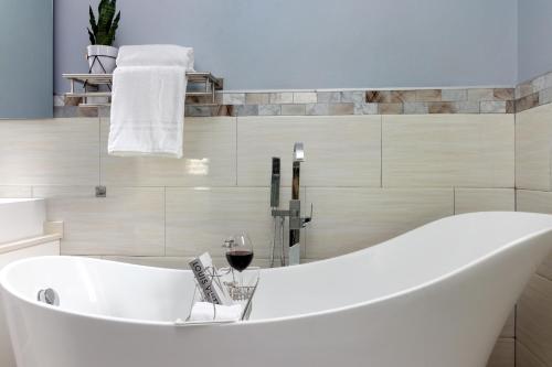 a white bath tub in a bathroom with a glass of wine at Coastal Escape in Riviera Tower Isle Beach Neaby in St Mary