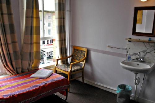 アムステルダムにあるホテル タマラの椅子、シンク、窓が備わる客室です。