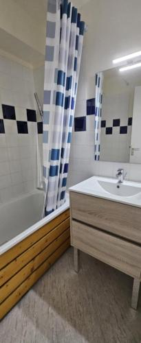 une salle de bain avec une baignoire, un lavabo et un miroir dans l'établissement Face Mer, à Fort-Mahon-Plage