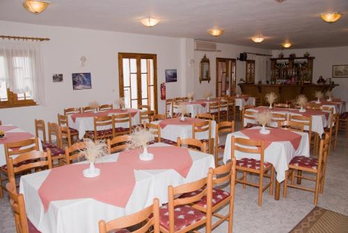 a room with tables and chairs with red and white tablecloths at Guesthouse Arsenis in Kalabaka