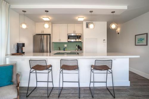 a kitchen with a counter with three bar stools at Sugar Beach 502 in Kihei