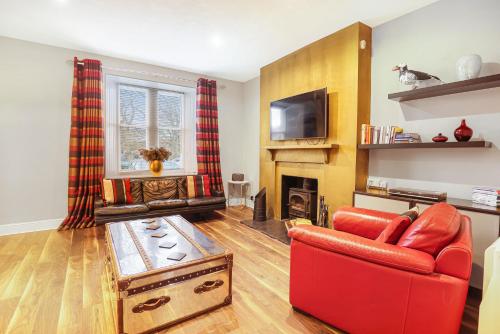 a living room with a red couch and a fireplace at Grove Cottage - North East Escapes in Bamburgh