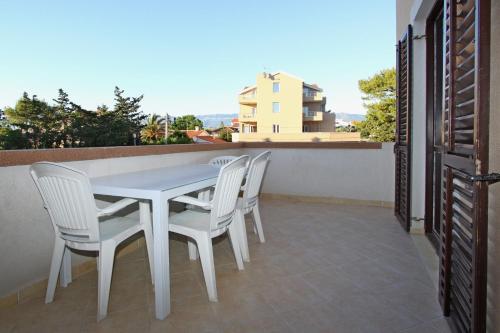 a white table and chairs on a balcony at Apartments and Rooms Vesna Novalja in Novalja