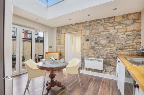a kitchen with a table and chairs and a stone wall at Grove Cottage - North East Escapes in Bamburgh