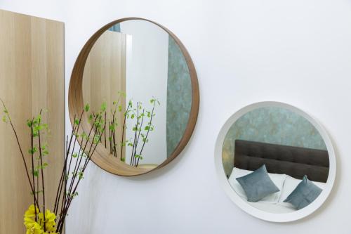 a mirror on a wall with a bed and a chair at Genoa Lux Apartments with parking in Genova