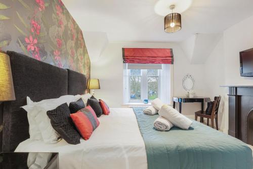 une chambre avec un grand lit avec des oreillers colorés dans l'établissement Grove Cottage - North East Escapes, à Bamburgh