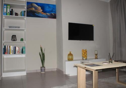 a living room with a table and a tv on the wall at Gwanxhae Boutique Accommodation in Maun