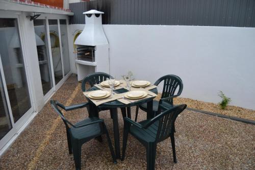 a table with four chairs and a stove on a patio at O Chalé Bela in Setúbal