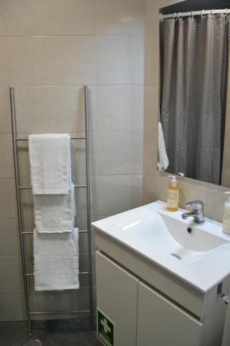 un bagno con lavandino, specchio e asciugamani di O Chalé Bela a Setúbal