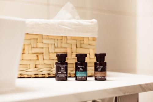 three bottles of essential oils sitting on a shelf next to a basket at Mnēmes Residence in Sozopoli