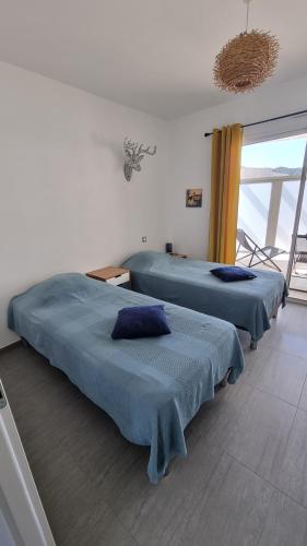 deux lits assis dans une pièce avec une fenêtre dans l'établissement Magnifique appartement traversant à 300 m de la plage, à Calvi