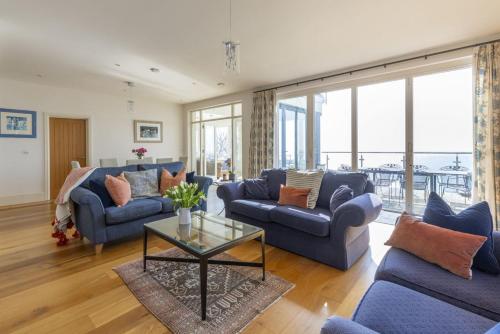 a living room with blue couches and a glass table at The Skerries in Stoke Fleming