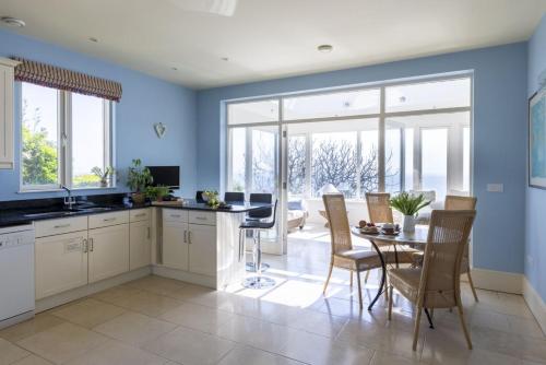 a kitchen with blue walls and a table and chairs at The Skerries in Stoke Fleming