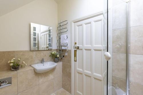 Un baño con lavabo y ducha con espejo. en The Skerries, en Stoke Fleming