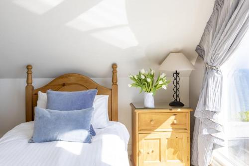 a bedroom with a bed with blue pillows and a window at The Skerries in Stoke Fleming