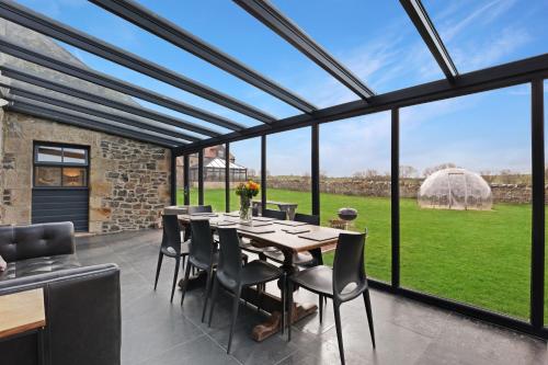 a dining room with a table and chairs and windows at Barn Cottage - North East Escapes in Bamburgh