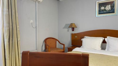 a hotel room with a bed and a chair at Hotel Peninsule Bonamoussadi Douala in Douala