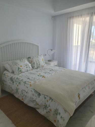 a white bedroom with a bed and a window at First line beach 2bedrooms appartment in Casares