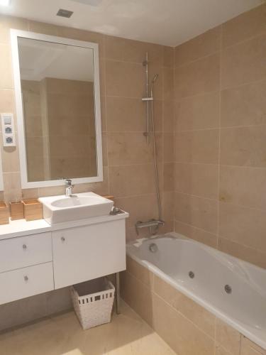 a bathroom with a sink and a tub and a mirror at First line beach 2bedrooms appartment in Casares