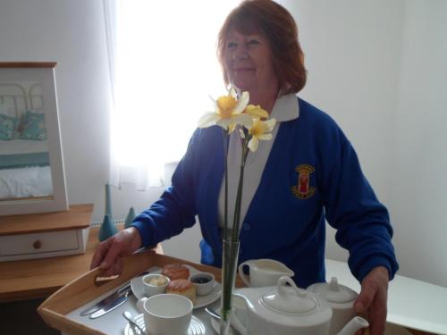 a woman standing in a kitchen with a tray of food at Padstow Bed & Breakfast in Padstow