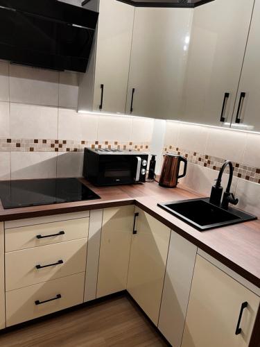 a kitchen with white cabinets and a sink and a microwave at Mokka Apartament Konin in Konin