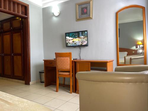 a living room with a couch and a mirror at Hotel Peninsule Bonamoussadi Douala in Douala