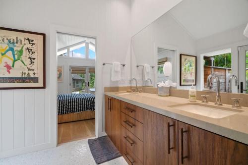 a bathroom with two sinks and two mirrors at Coconut Hut in Kilauea