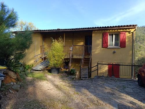 une maison jaune avec des fenêtres rouges et une allée. dans l'établissement Gite des Suvieres, à Les Mayons