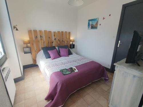 - une chambre avec un grand lit et des oreillers violets dans l'établissement Le Tartaret - Murol, à Murol