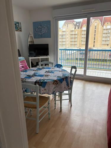 une salle à manger avec une table et des chaises et un balcon dans l'établissement Appartement proche mer, à Cucq