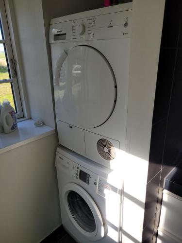 a washer and dryer in a room with a window at Lejbølle Gamle Bageri in Tranekær