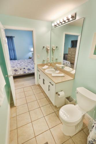 a bathroom with a toilet and a sink and a mirror at Lake Town Charming Condo Steps from the Beach in Panama City Beach