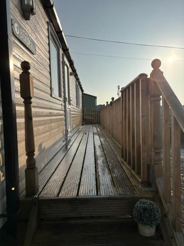 a wooden deck with a building and a potted plant at The Lookout 3 Bedroom Family Caravan with Sea View Pet Friendly in Aberystwyth