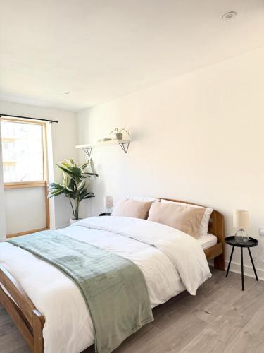 a white bedroom with a large bed and a window at Modern Apartment - Free Parking in London