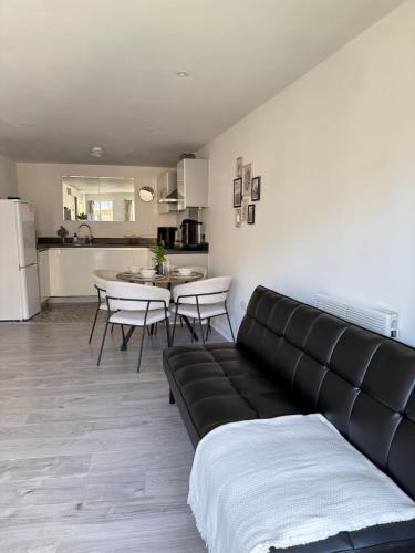 a living room with a couch and a table and a kitchen at Modern Apartment - Free Parking in London