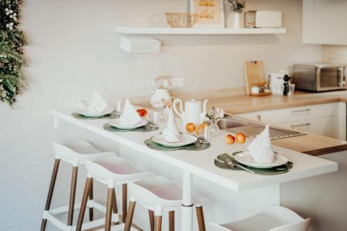 a kitchen with a white table with chairs and a table set with food at 4 seasons house in Malmedy