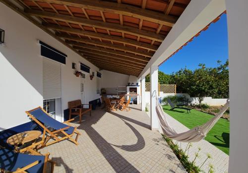 a patio with chairs and a hammock on a house at Casa do Chafariz - Guest House in Cercal