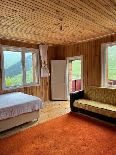 a bedroom with a bed and a couch and windows at DORUK Pansiyon in Çaykara