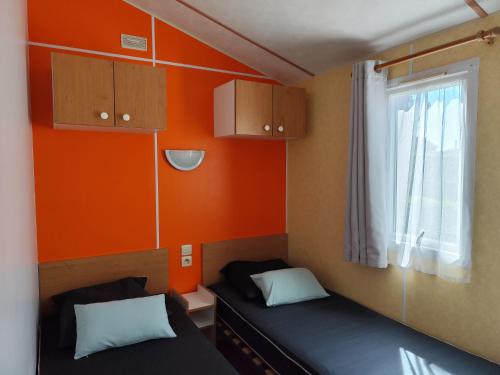 une petite chambre avec deux lits et une fenêtre dans l'établissement Cosy Lili - Mobilhome RESPIRO - Pleine nature, plage à 250mn, à Damgan