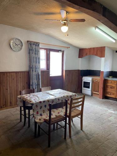 une cuisine avec une table et des chaises et une horloge au mur dans l'établissement Grange, à Saint-Paul-Mont-Penit