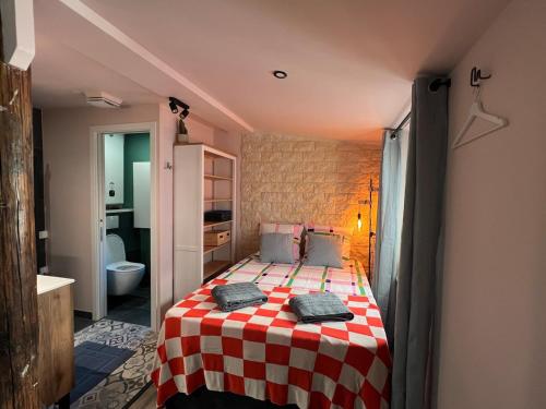 - une chambre dotée d'un lit avec une couverture rouge et blanche en damier dans l'établissement Cozy studio in Menton old town - near parking, à Menton